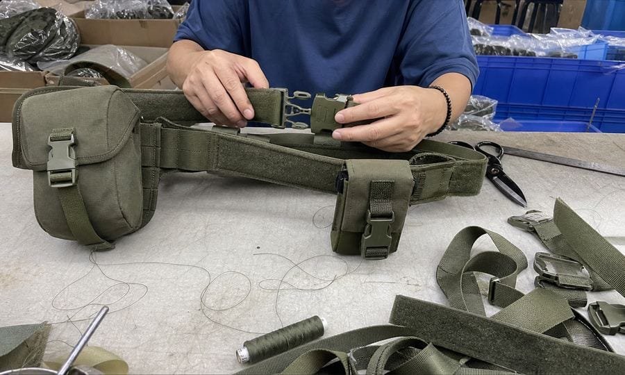 worker fitting the buckle on a modular tactical belt during sample assembly